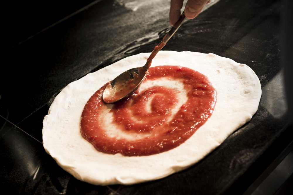 Preparazione della pizza con pomodoro al Ristorante Emporio